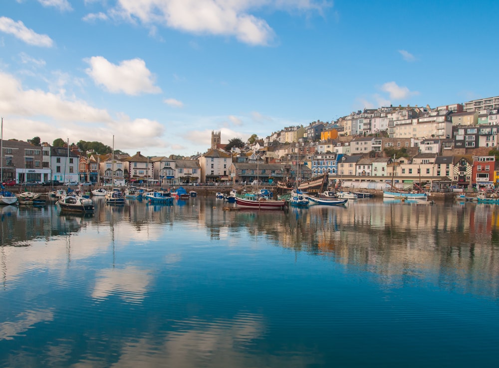 boats on calm body of water surrounded by building under white and blue cloudy sky