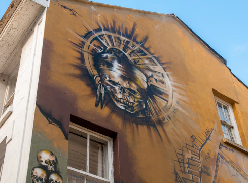 A mural painted in black, red, and yellow featuring bold shapes and small floating skulls in the background.