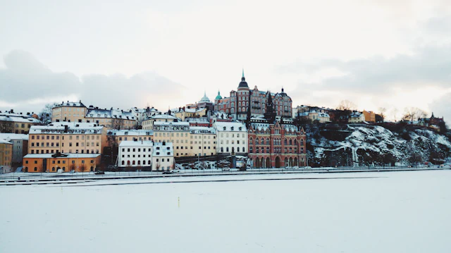 The Södermalm skyline rising above a snow-covered waterfront, with Katarina Church's tower among the historic buildings on the ridge.