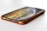 A smartphone lies flat on a surface, partially encased in a brown protective cover. The device's screen is on, displaying a swirling pattern of warm colors like yellow and orange. The phone is positioned at an angle showing the speaker grille and lightning port clearly.