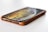 A smartphone lies flat on a surface, partially encased in a brown protective cover. The device's screen is on, displaying a swirling pattern of warm colors like yellow and orange. The phone is positioned at an angle showing the speaker grille and lightning port clearly.