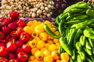 Close-up of colorful vegetables like bell peppers, carrots, and leafy greens stacked neatly.