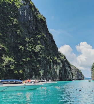 white motorboat in body of water near the mountain during daytime