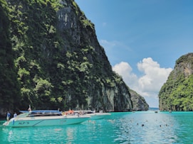 white motorboat in body of water near the mountain during daytime