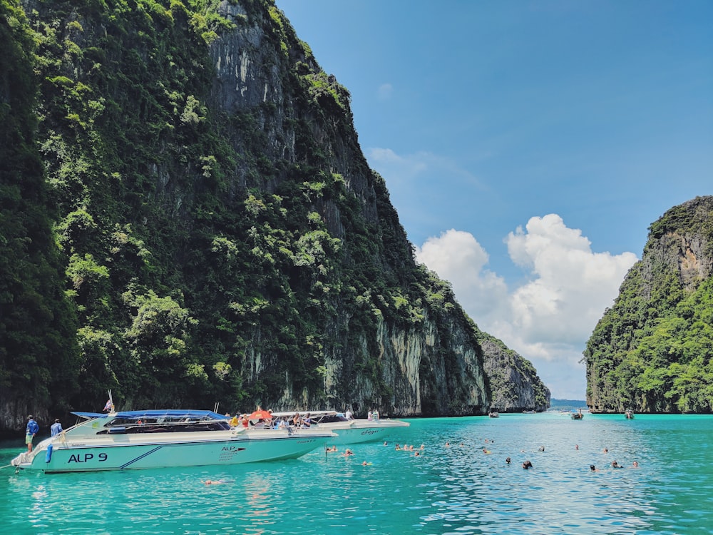 white motorboat in body of water near the mountain during daytime