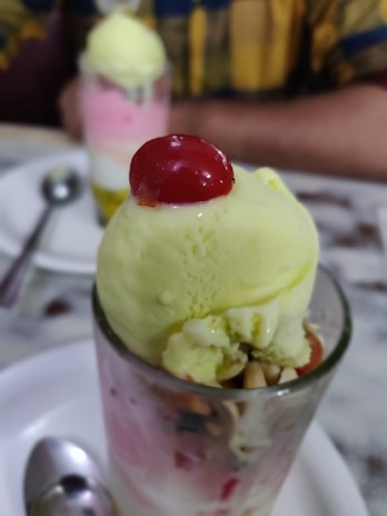 A close-up of a sunny sundae topped with cherries and sprinkles on a colorful napkin at the ice cream counter.