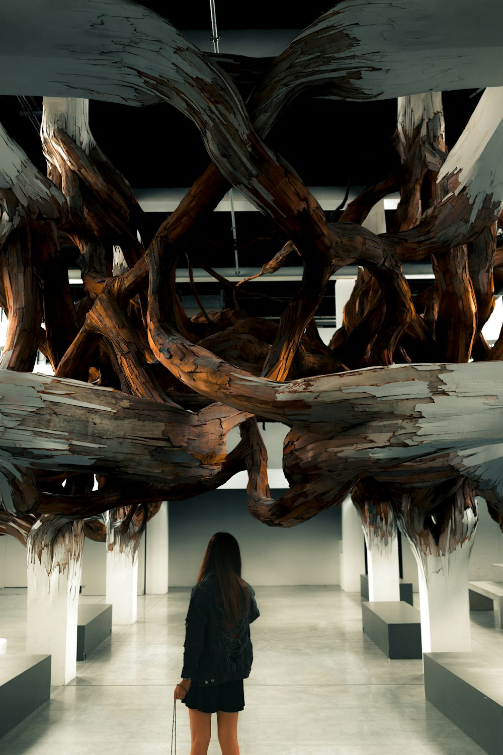 woman in black jacket standing under wood art