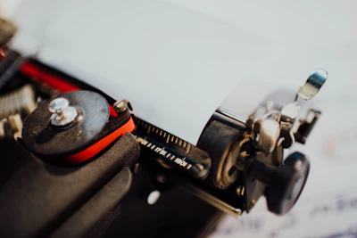 A close-up of a vintage printer being carefully serviced with tools on a wooden desk.