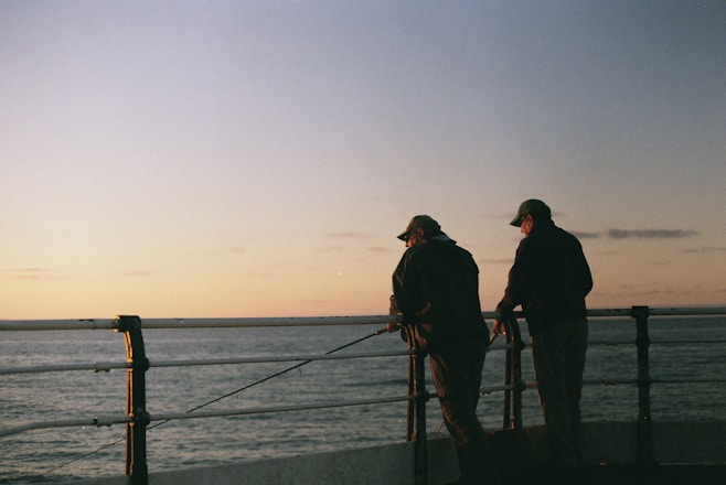 two men fishing by the railing
