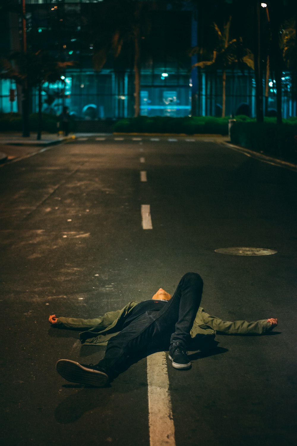 man laying down on road during nighttime