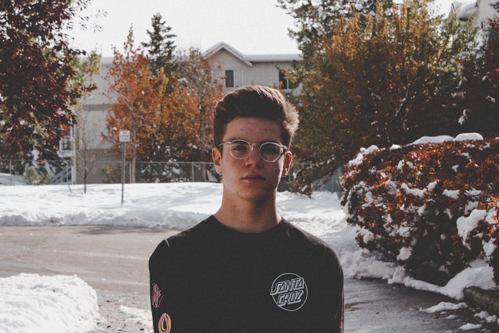 a young man standing in front of a snow covered street