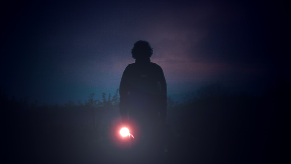 uma pessoa em pé no escuro com uma lanterna na mão