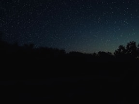 A serene night sky filled with shimmering stars over a peaceful landscape