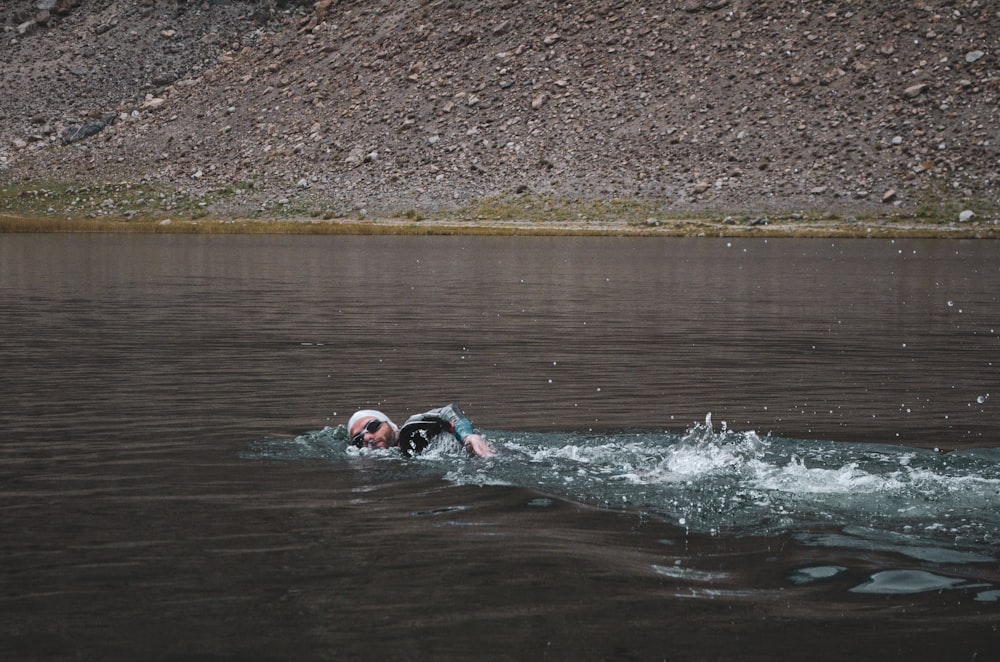 man swimming on body of water