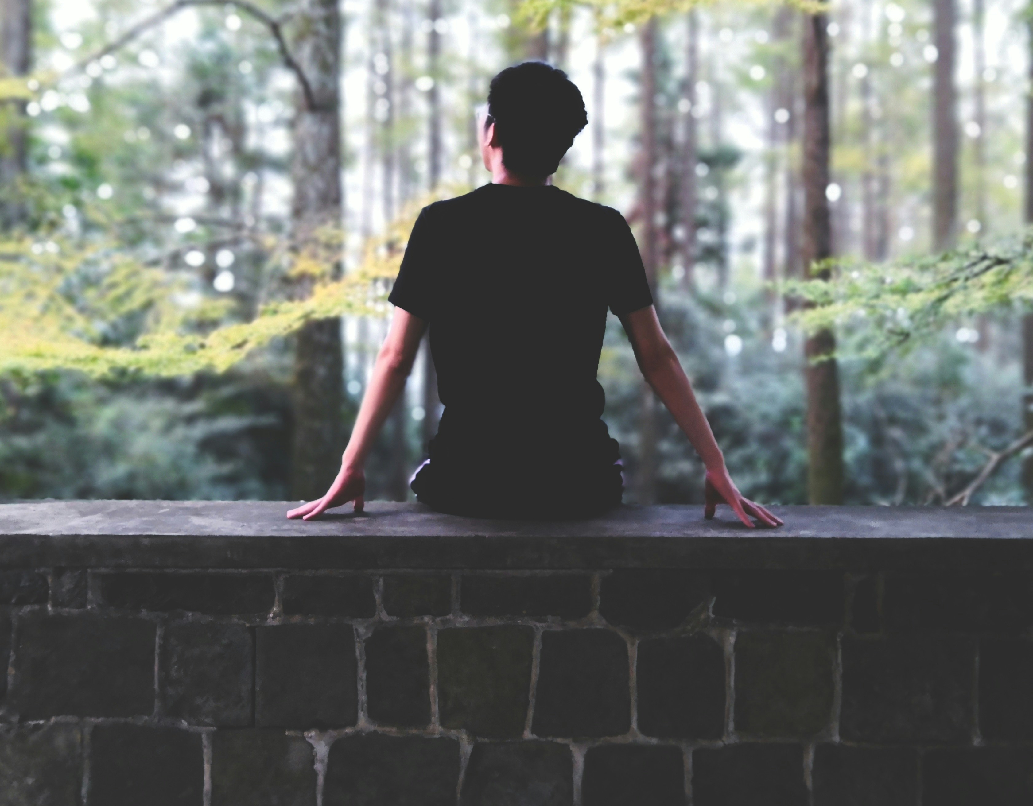 man sitting on brown concrete bench during daytime
