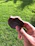 Close-up of a hand holding a crunchy millet biscuit with a soft beige background.