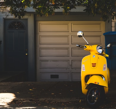 yellow motor scooter parked near white garage door