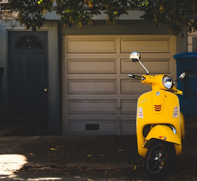 yellow motor scooter parked near white garage door