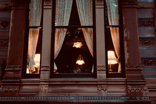 Close-up of stylish drapes framing a window in a warmly lit room.
