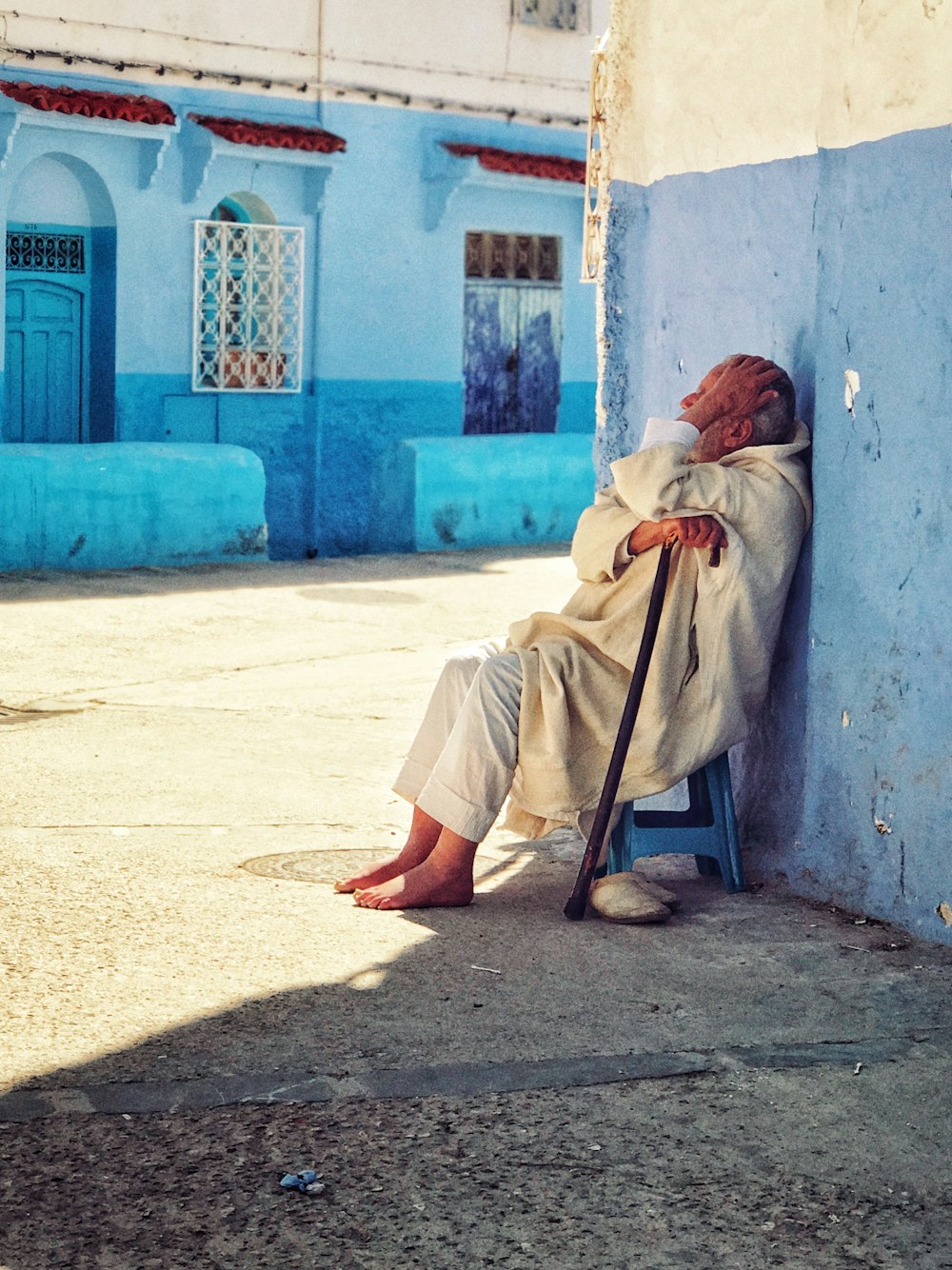 woman sitting on blue stool while holding black cane outdoor during daytime