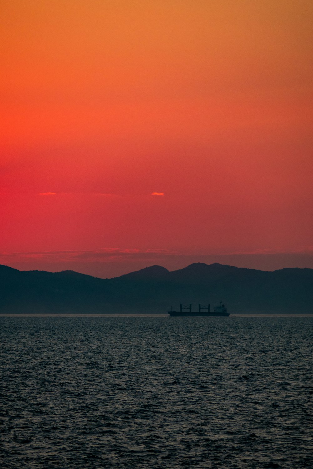 ゴールデンアワーの海に浮かぶ船のシルフート写真