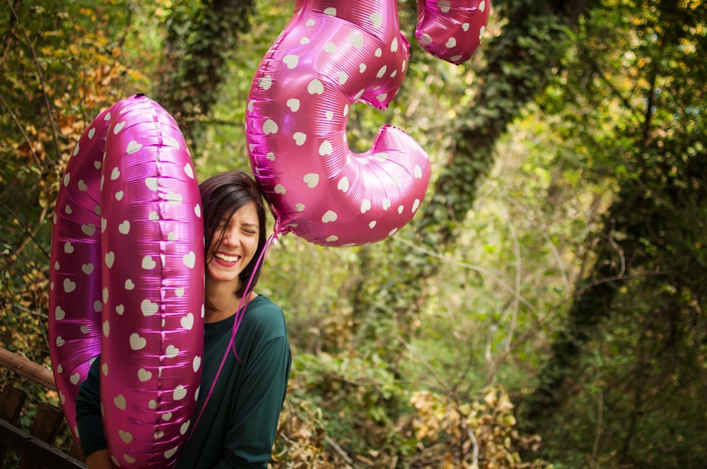 smiling woman holding red-and-white balloons outdoors during daytime