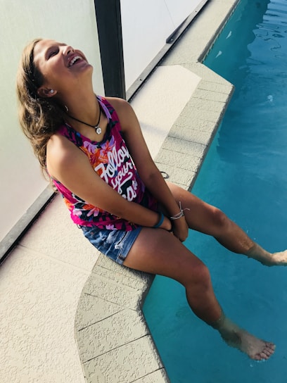 A joyful little girl jumping into a sparkling swimming pool on a sunny day.