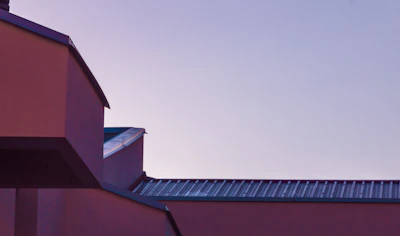 Modern architectural exterior featuring minimalist shapes and soft mauve accents at dusk.