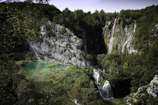 A serene view of turquoise waterfalls cascading over lush green rocks at Plitvice Lakes.