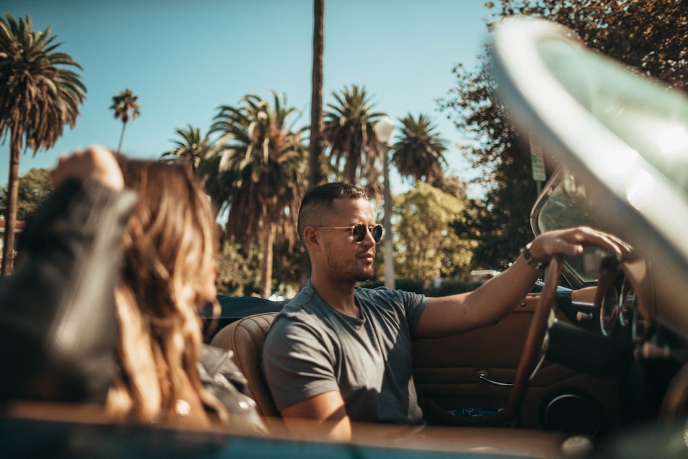 man driving convertible beside woman