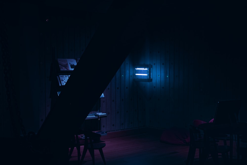 a dark room with a neon light shining on the wall
