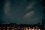 A serene night sky filled with stars and a glowing full moon over a mystical forest.