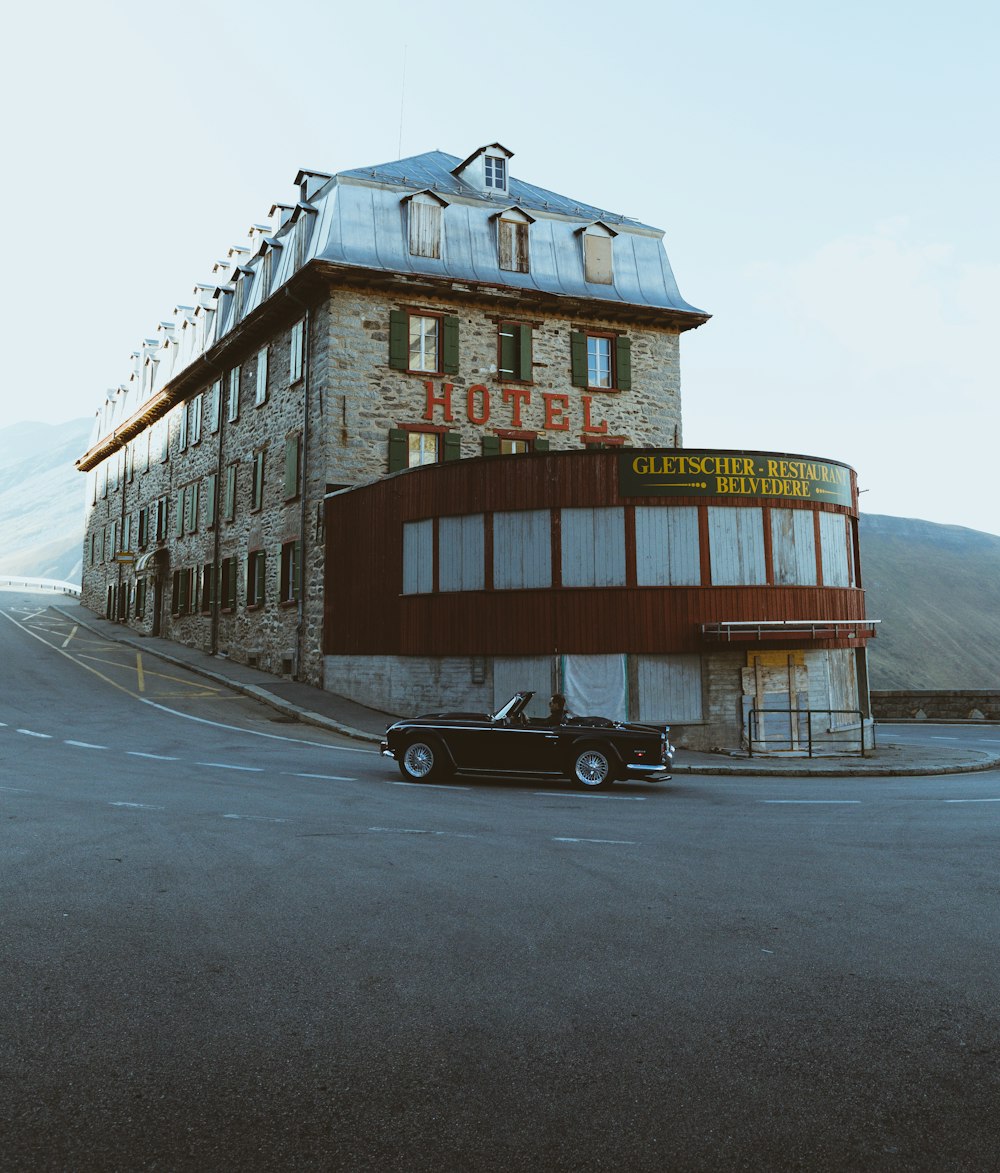 a black car parked in front of a hotel