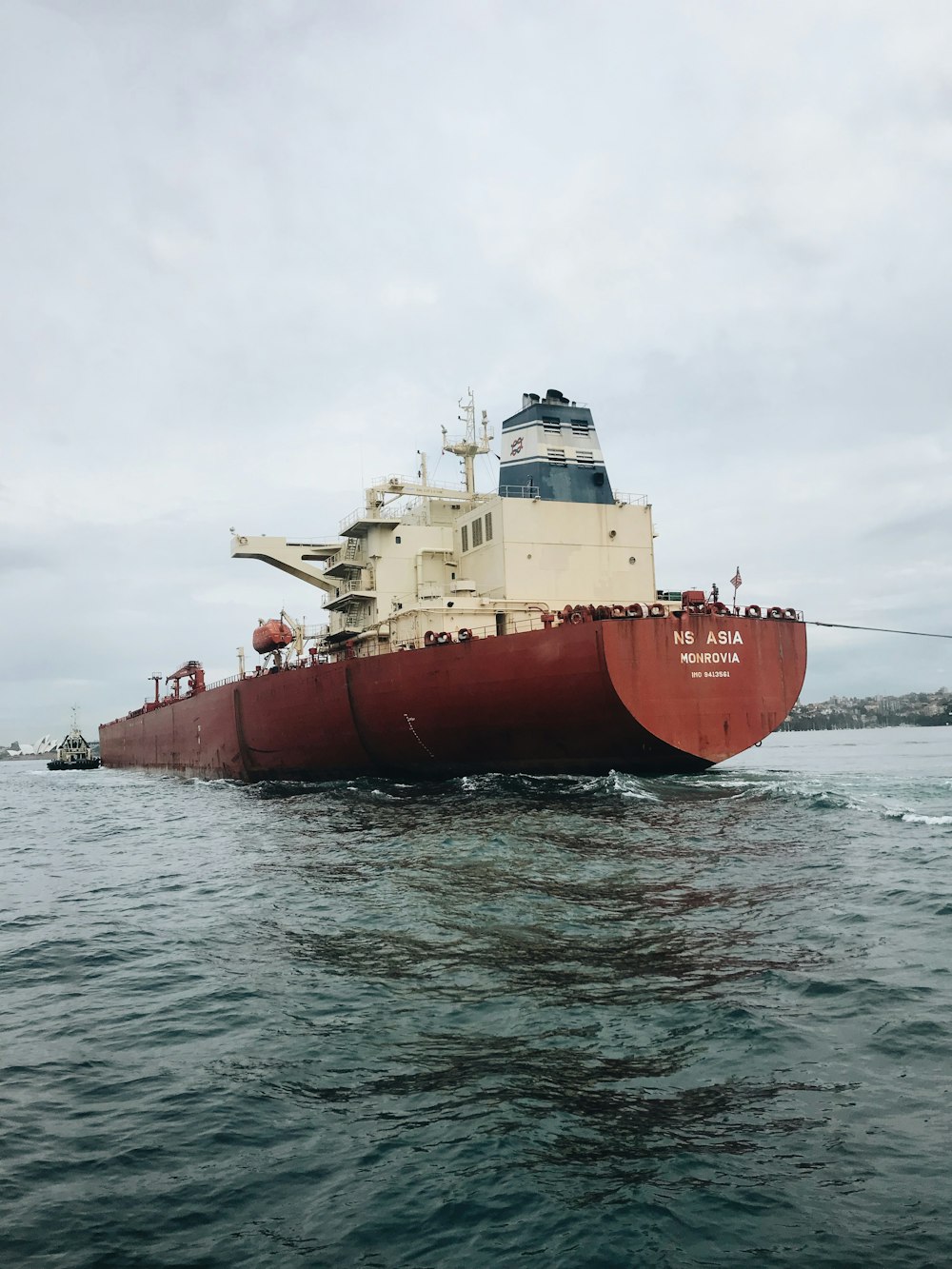 navio vermelho e branco flutuando no corpo de água durante o dia