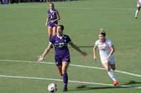 Close-up of a female player dribbling the ball with determination during a match.