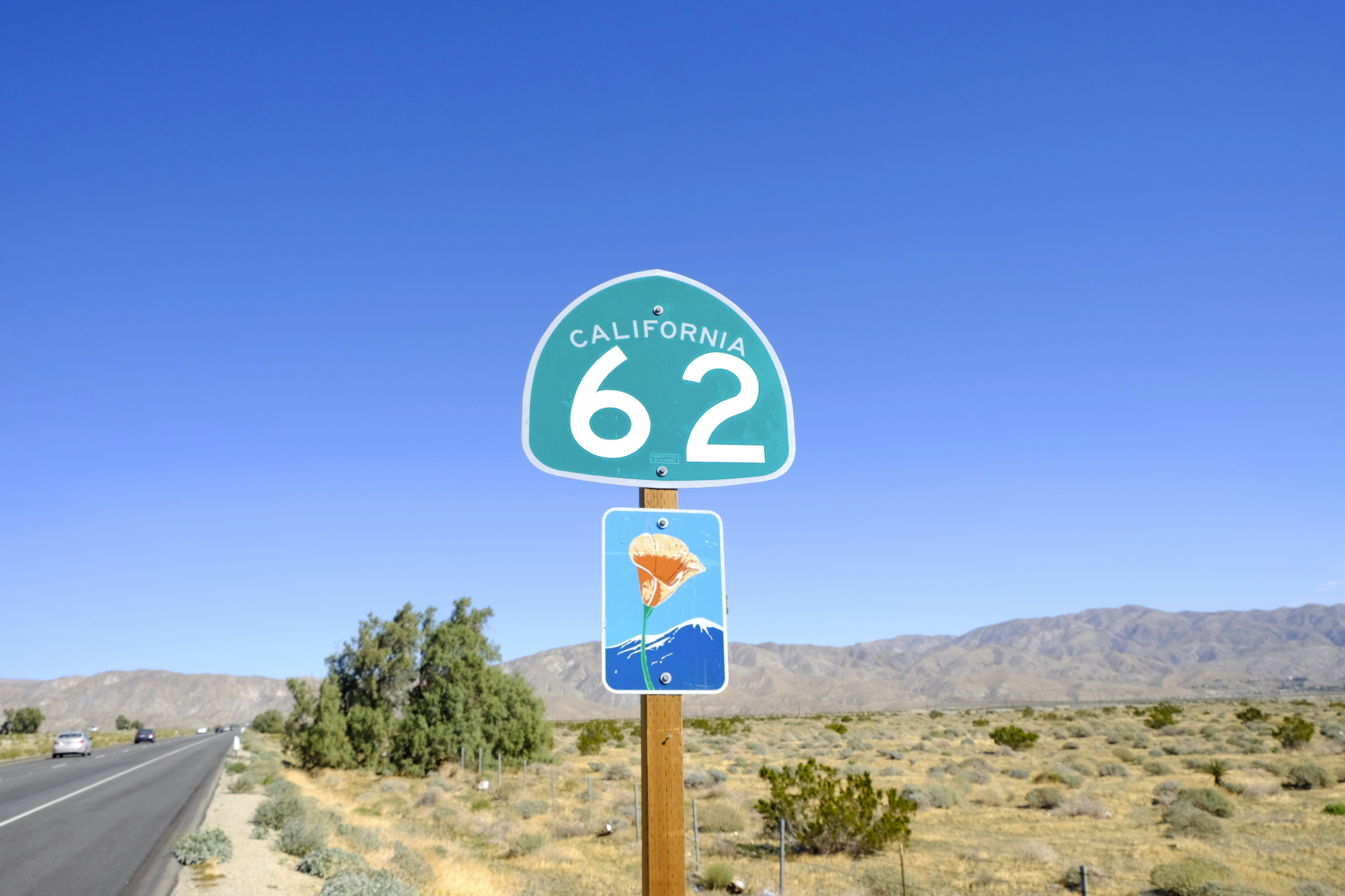 A sign in a desert for California Route 62 against a blue sky