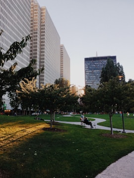 Contemporary urban park with greenery, benches, and walking paths at sunset.