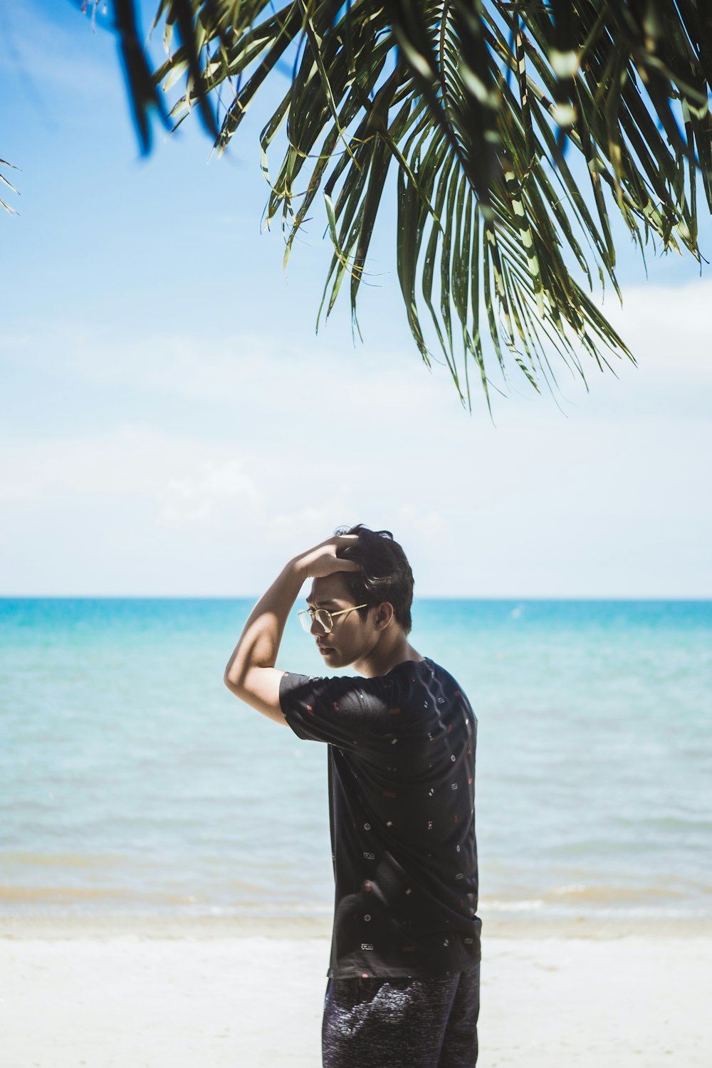 man on sand beach under palm tree
