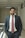 man wearing formal suit with both hands on pockets standing beside railings