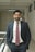 man wearing formal suit with both hands on pockets standing beside railings