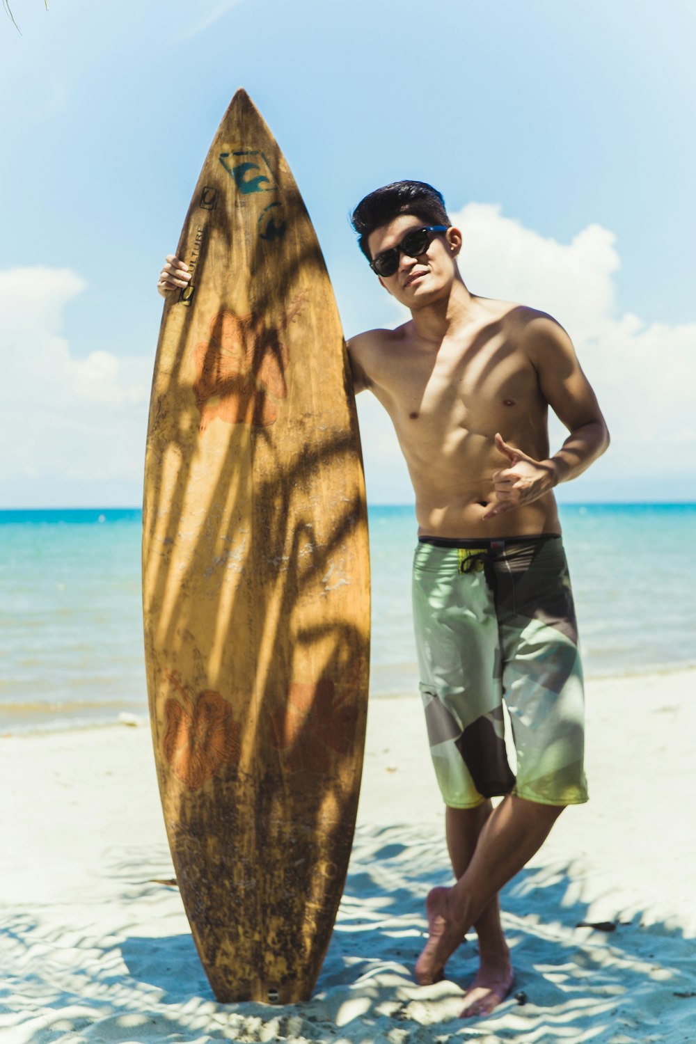 a man standing next to a surfboard on a beach