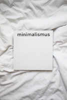 Close-up of a minimalist white book cover with delicate typography on a wooden table