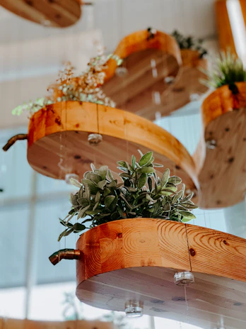 Wood-grain-effect hanging planters swaying gently among lush courtyard greenery.