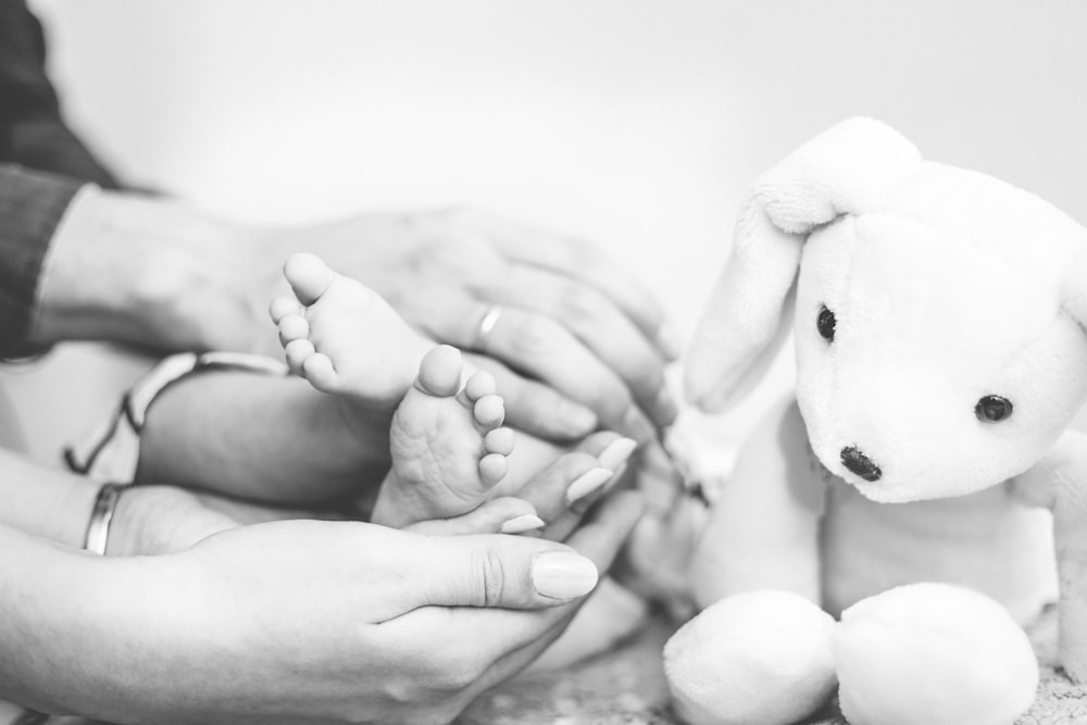 grayscale photography of person's hands holding baby's feet