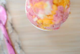 A colorful scoop of creamy vanilla ice cream in a pastel pink bowl.