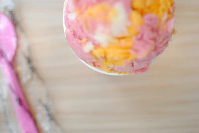 A colorful scoop of creamy vanilla ice cream in a pastel pink bowl.
