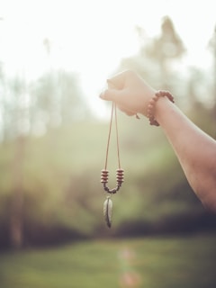 A lightweight charm pendant necklace draped casually over a beige sweater against a cozy backdrop