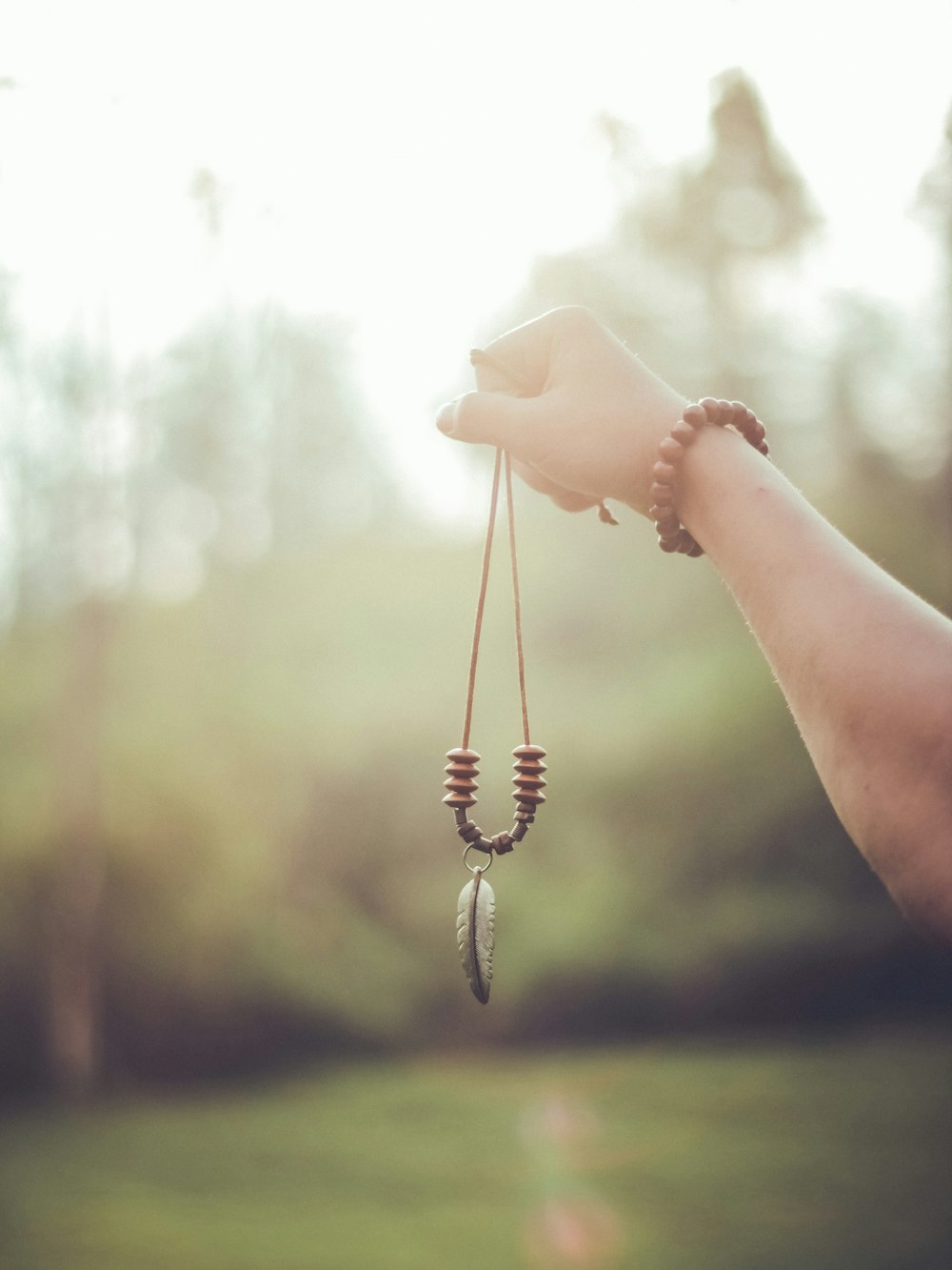 person holding brown beaded pendant