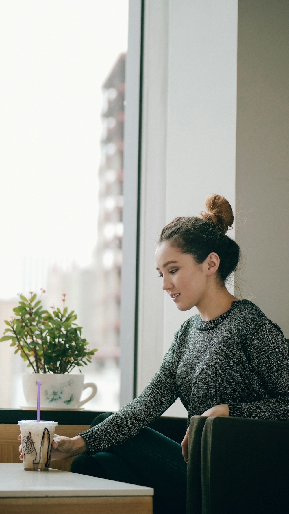 woman in gray long-sleeved shirt sitting beside table