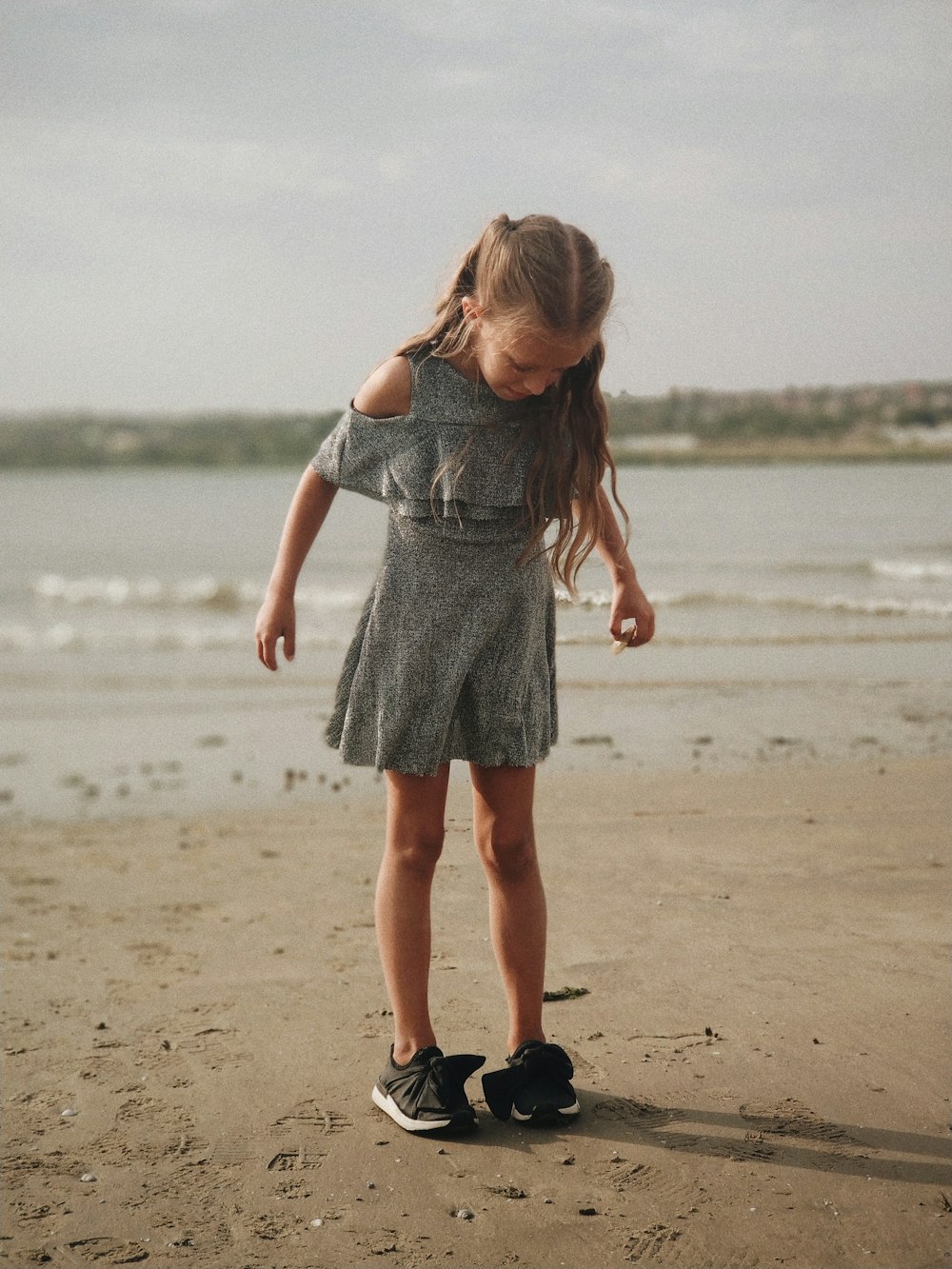 girl wearing gray dress standing on shore